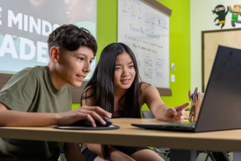 preteen boy and girl working together coding on a laptop